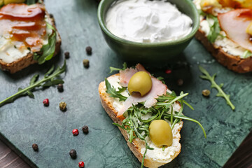 Board with delicious sandwiches and cream cheese, closeup