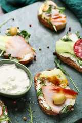 Board with delicious sandwiches and cream cheese, closeup
