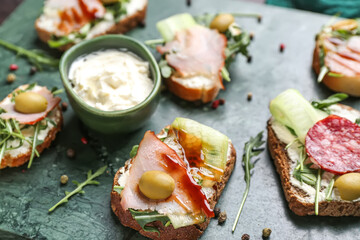 Board with delicious sandwiches and cream cheese, closeup