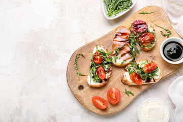 Wooden board with delicious sandwiches and sauce on light background
