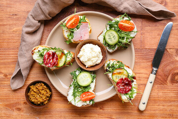 Plate with delicious sandwiches, cream cheese and mustard on wooden table