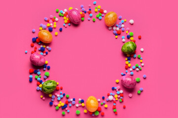 Frame made of Easter eggs with pompoms on pink background