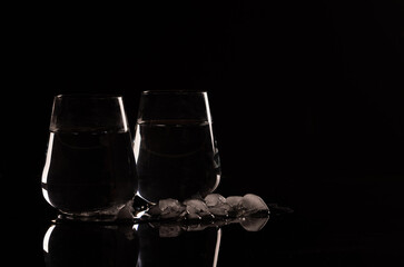 Pair of Glasses Filled with Water on Black Background and Crushed Ice - Hydration Theme