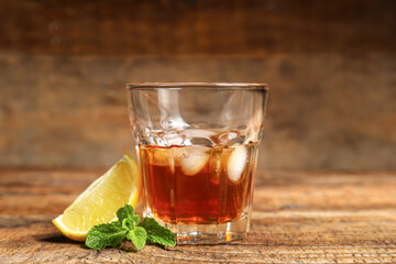 Glass of rum with lime an mint leaves on wooden background