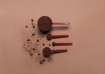 Spoons of coffee powder and beans on brown background