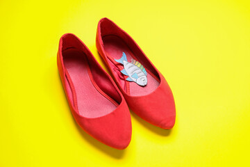 Female shoes with paper fish on yellow background. April Fools' Day celebration
