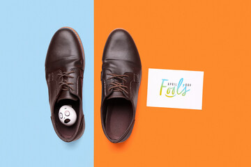 Paper with text APRIL FOOL'S DAY and male shoes on color background