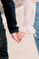 An engaged couple hold hands while they walk.
