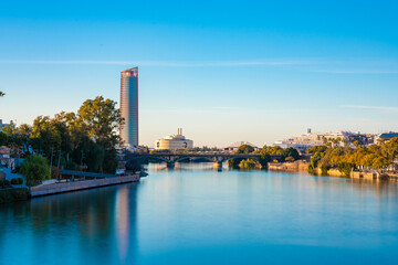 Obraz premium Long exposure of torre de sevilla and bridge crossing the Canal de Alfonso XIII, seville, spain