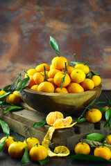 Mandarin orange on rustic wooden bowl and dark wooden background. 
