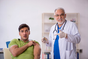 Young male patient visiting old male doctor in vaccination conce