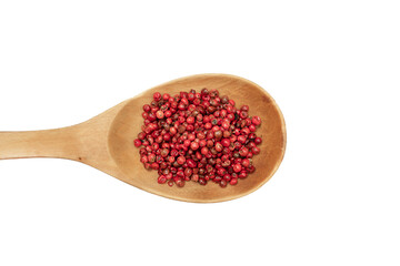 Pink pepper in wooden spoon isolated