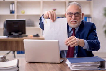 Obraz premium Old male employee working in the office
