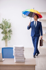 Young male employee holding an umbrella in the office