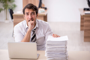 Young male employee unhappy with excessive work in the office