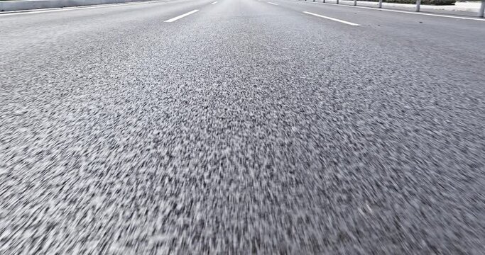 close-up cinematic POV shot of an asphalt road. Car is driving on the highway.