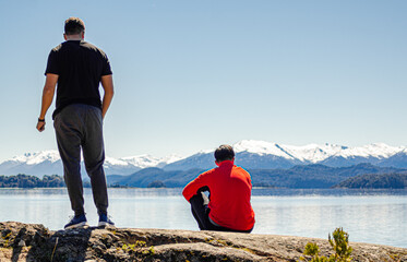 amigos sobre una roca mirando el paisaje de montañas nevadas y lagos