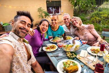 Happy group of friends laughing taking selfie during barbecue dinner party outdoors.