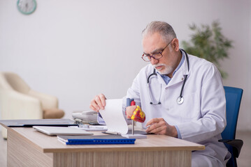 Old male doctor cardiologist working at the hospital