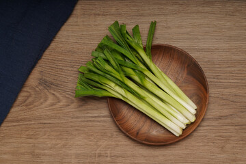 A pile of green onions on a wooden plate