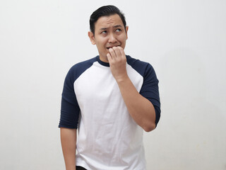 Nervous Asian man biting his nails as if he is worried afraid of something bad