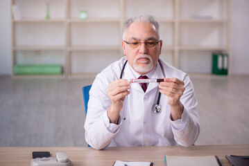 Old male doctor hematologist working in the clinic