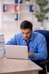 Fototapeta premium Young male employee and too much work in the office