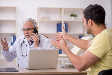 Fototapeta premium Young male patient visiting old male doctor