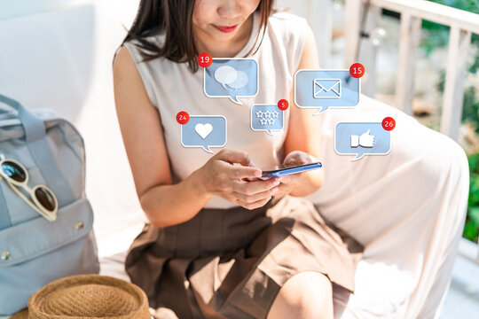 Young woman using mobile phone with Social media interactions and notification icons while traveling for summer vacation