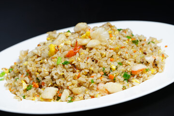 A plate of seafood scary Yangzhou fried rice on black background