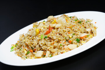 A plate of seafood scary Yangzhou fried rice on black background