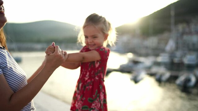 Mom with a little girl dancing on the pier holding hands