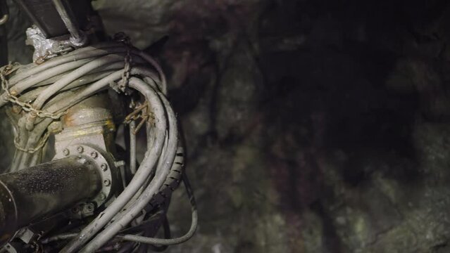 Professional drilling equipment makes holes for setting explosives in rock. Machinery with coolant operates in ore mine to extract minerals closeup