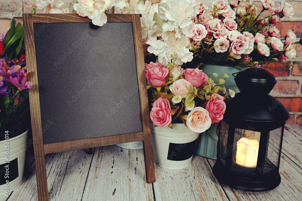 Poster easel blackboard empty mock up space for copy with flower decoration on wooden background