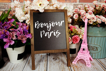 Bonjour Paris text message write on chalkboard with pink Eiffel tower souvenir and flower blooming © may1985