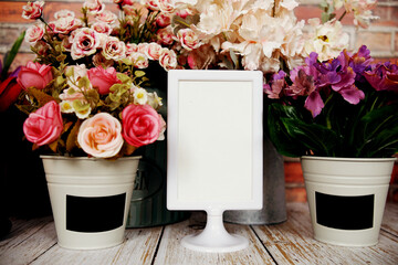 Mock up empty paper card with artificial flower decoration on wooden background