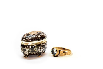 Small black and white ceramic jewelry box with a gold ring on the neck and a gold ring with a diamond on it.