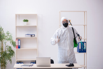 Fototapeta premium Young male contractor disinfecting office during pandemic