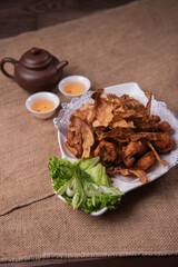 deep fried crispy golden chicken meat with ginger slices and garlic on wood table chinese tea pot asian halal banquet menu
