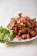 deep fried crispy golden chicken meat with ginger slices and garlic on wood table chinese tea pot asian halal banquet menu