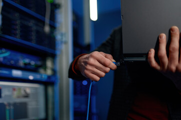IT technician switching wire to laptop computer closeup