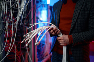 IT man with bunch of cables in hands in server room - Powered by Adobe