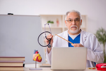 Old male doctor cardiologist working in the clinic