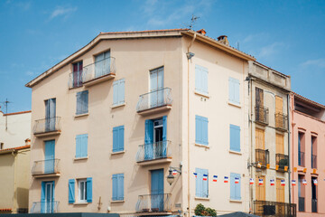 Obraz premium Une façade d'immeuble à Collioure. Un bâtiment à Collioure. Immeuble du sud de la France. Maison méditerranée. Une façade rose avec des fenêtres bleues.