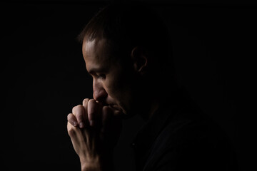 Portrait of a handsome man praying over gray background