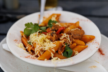 plate of spicy tomato pasta with steak and cheese