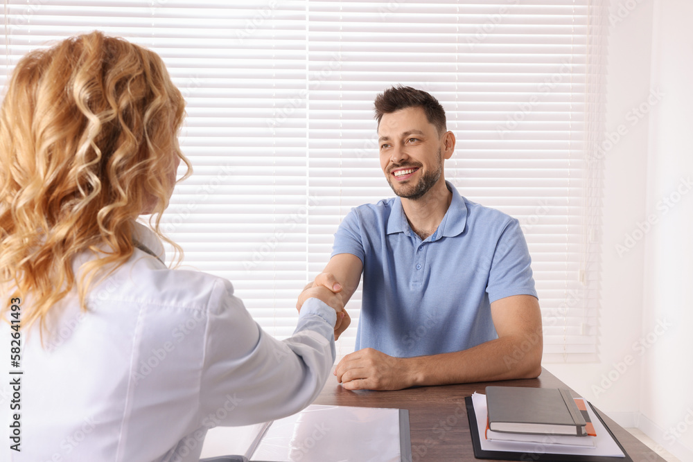 Wall mural Doctor shaking hands with patient in clinic