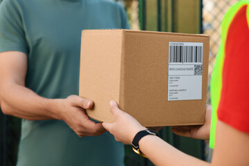 Man receiving parcel from courier outdoors, closeup