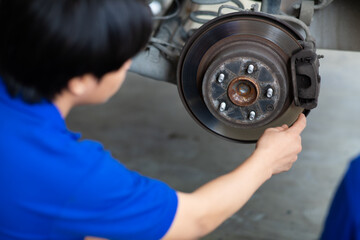 Asian man mechanic changing car wheel at Car maintenance and auto service garage. Young male worker people