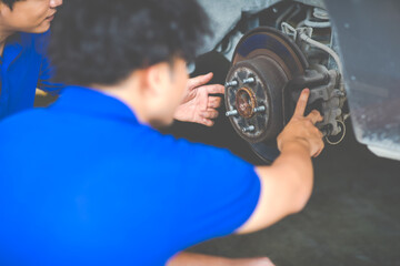 Asian man mechanic changing car wheel at Car maintenance and auto service garage. Young male worker people